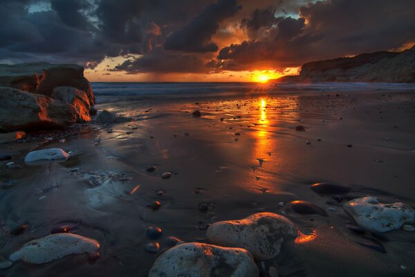 Dark landscape with sea rocks clouds and sunrise