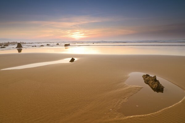 Verlassener Strand nach Ebbe vor dem Hintergrund des Sonnenuntergangs