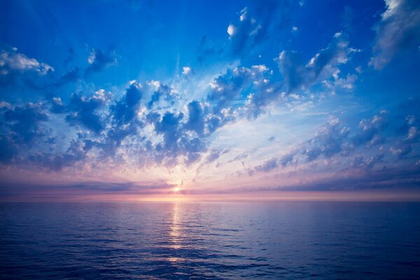 El sol que desaparece más allá del horizonte en la frontera del mar y el cielo nublado