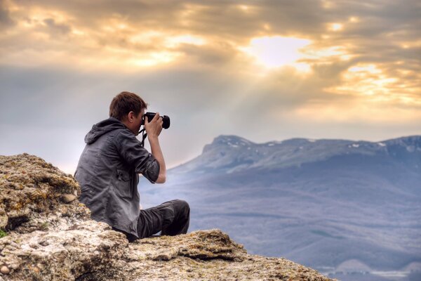 Фотограф на высоте фотографирует горы