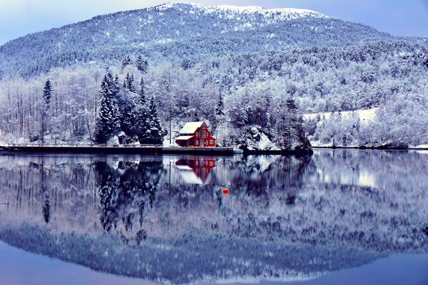 Red house on the shore of the lake among the snow