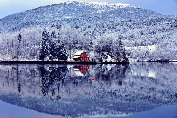 Czerwony dom nad jeziorem wśród śniegu