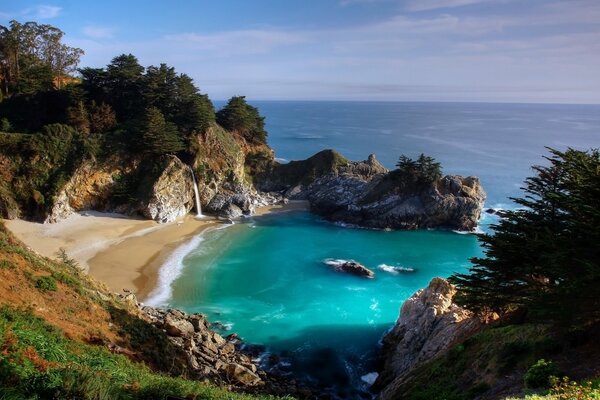 Azure beach in the rocks with a waterfall