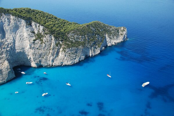 Jachty i żaglówki w błękitnej wodzie morze w pobliżu góry pokrytej zielenią. Grecja