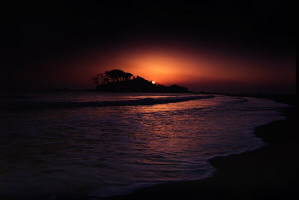 Sombría puesta de sol junto al mar con las sombras del islote