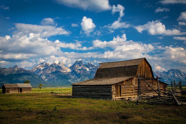 Houses on meadows against the background of mountains and the sky with cumulus clouds