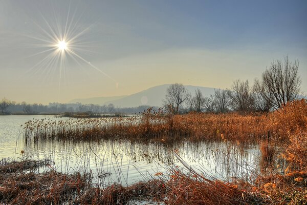 Il sole autunnale tramonta dietro il fiume