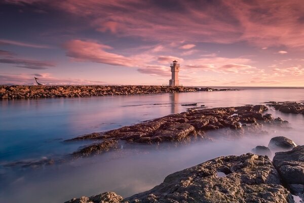 Faro en el mar con una hermosa puesta de sol