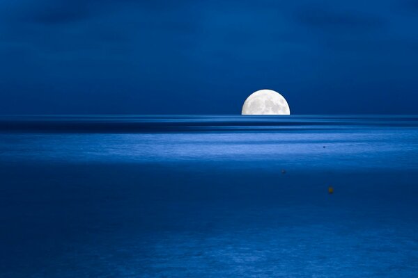 Half of the moon on the horizon above the sea