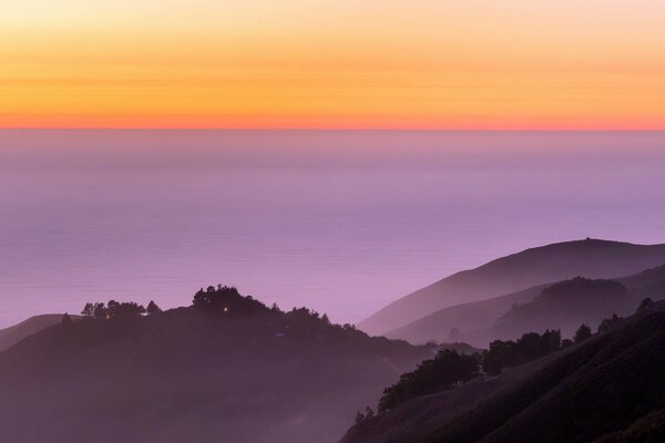 Kontrast fioletowych wzgórz i pomarańczowego zachodu Słońca