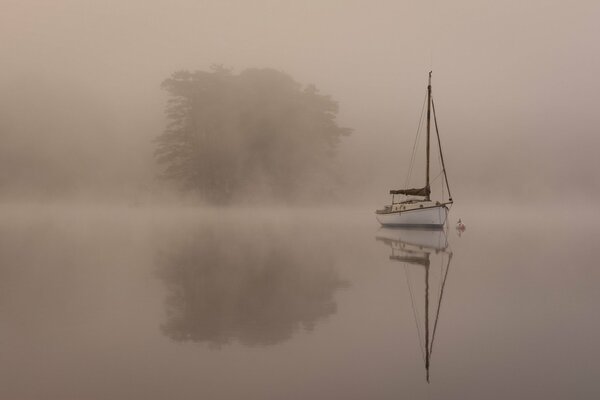 Yate en la niebla del lago de la mañana