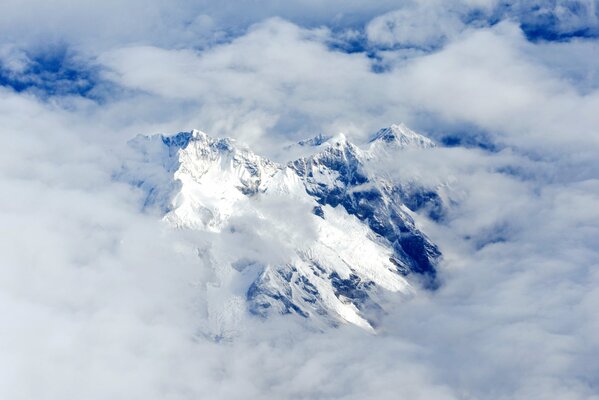 Clouds on top of a snowy mountain