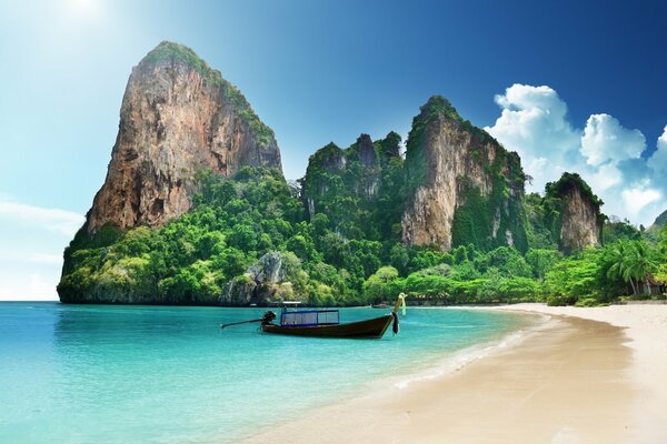 The boat is rocking on the ocean waves against the background of a cliff