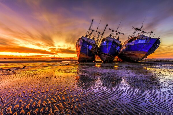 Majestuosa puesta de sol del mar y tres barcos vacíos