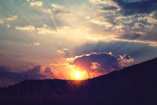 Le soleil se couche dans les nuages sur les collines