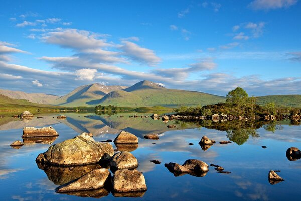 Stones on the lake shore against the background of mountains and clouds