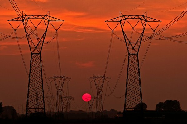 Silhouetten von Stromleitungsstützen bei Sonnenuntergang