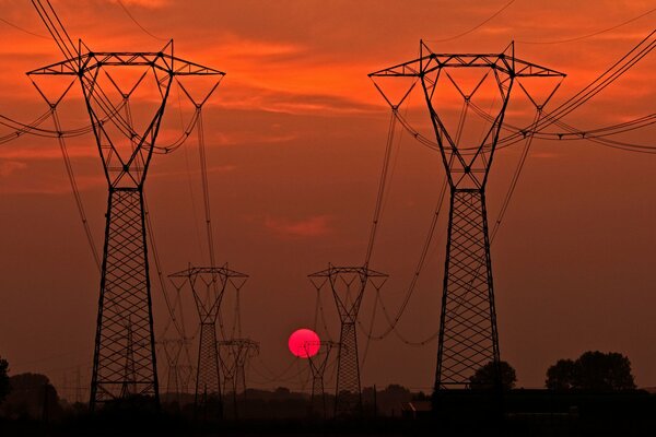Silhouettes de supports de lignes électriques au coucher du soleil