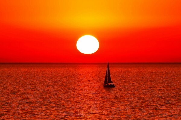 Sail in the sea on the background of sunset