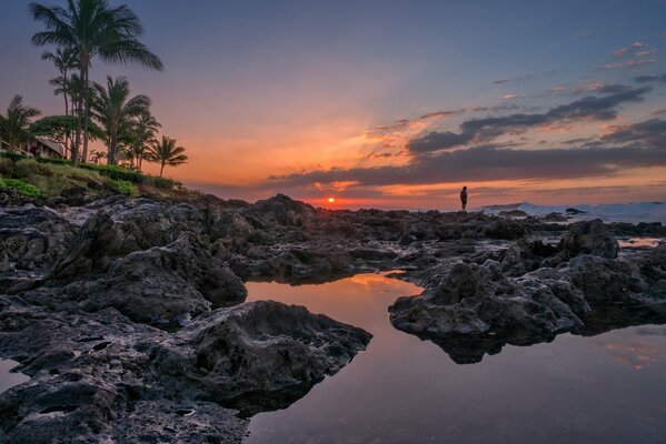 Sonnenuntergang vor dem Hintergrund eines felsigen Strandes