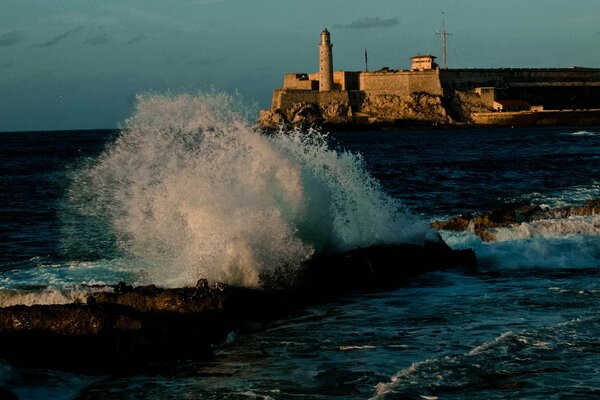 Salpicando las olas en el mar con un faro en la distancia