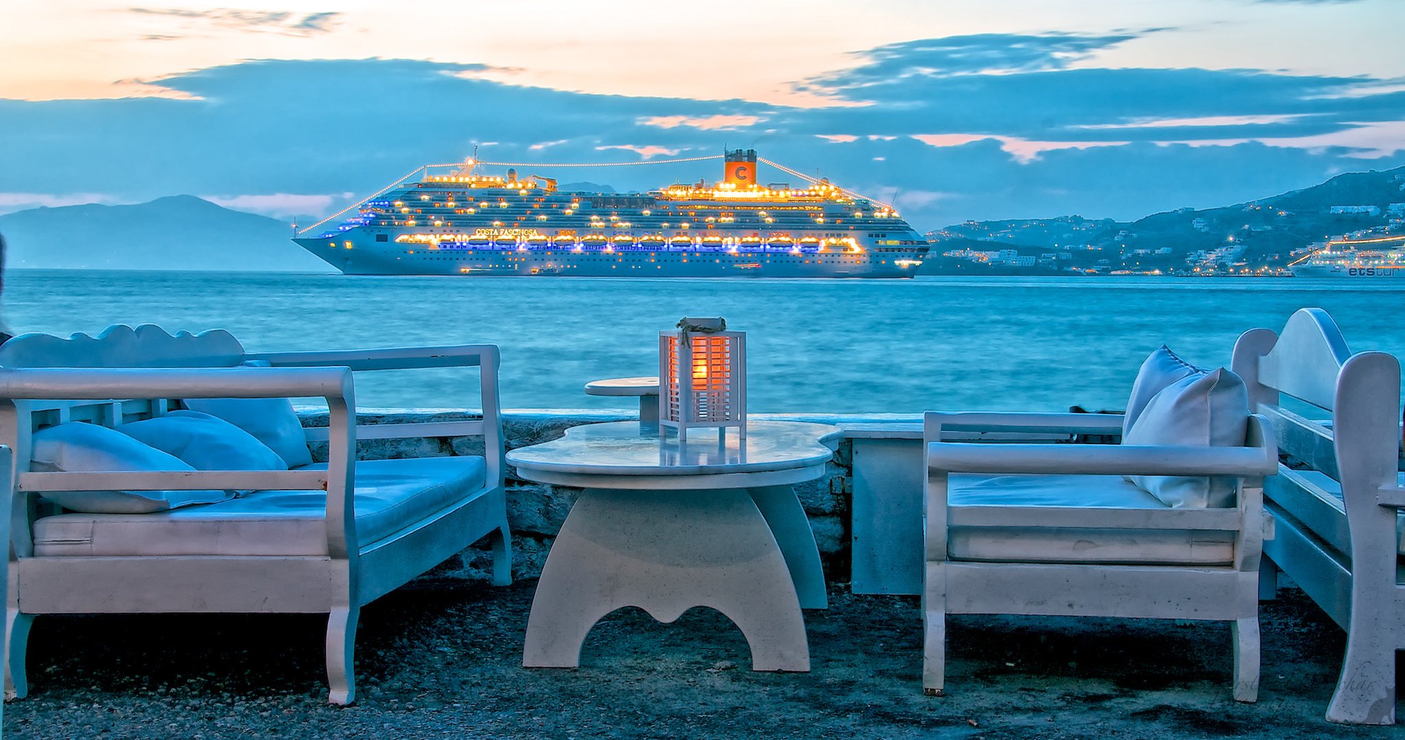 grèce île de mykonos ciel mer nuages montagnes soirée lumières paquebot navire chaise table loisirs