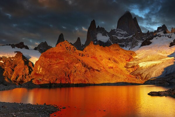 Sunrise on a lake surrounded by snow-capped mountains