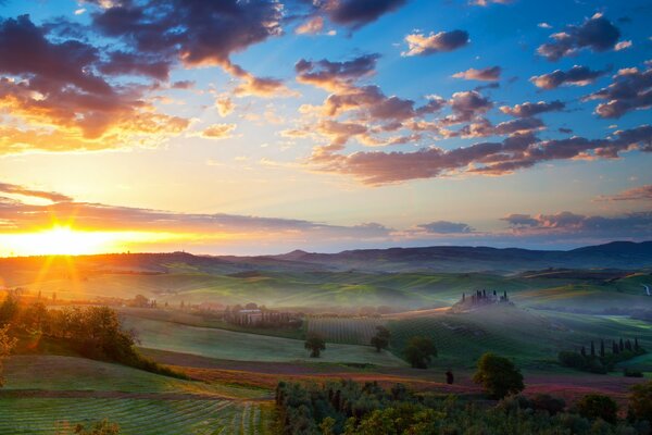 Nebbia sulla valle con il villaggio al tramonto