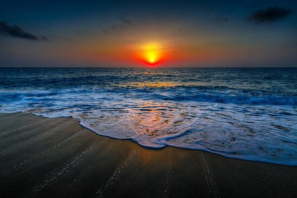 The sun goes below the horizon of the ocean