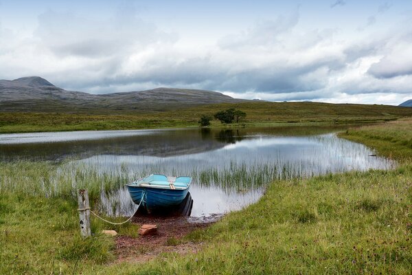 A lake with a tied boat in the hills of the mountains