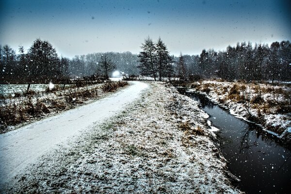 Winter road through the forest along the ditch