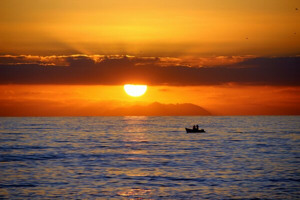 Deux dans un bateau dans la mer au coucher du soleil