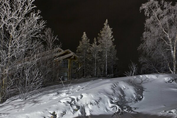 Ein Haus in den Bergen inmitten von Bäumen, die mit Schnee bedeckt sind