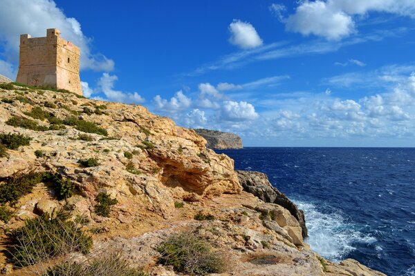 A lonely fortress stands on a clay shore above a deep blue sea