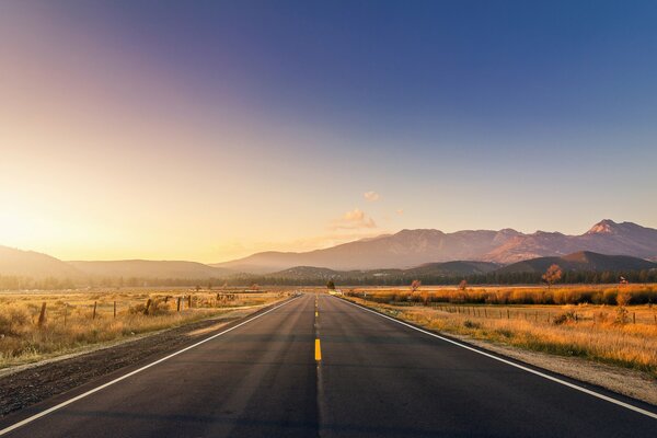 El camino en el fondo de la puesta de sol se va a la distancia