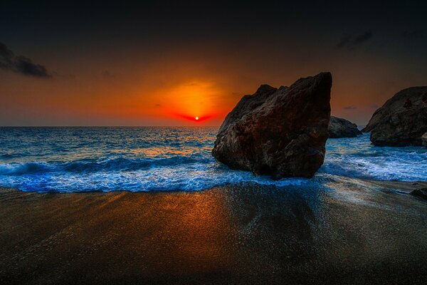 Grandes piedras en el fondo de la puesta de sol del mar