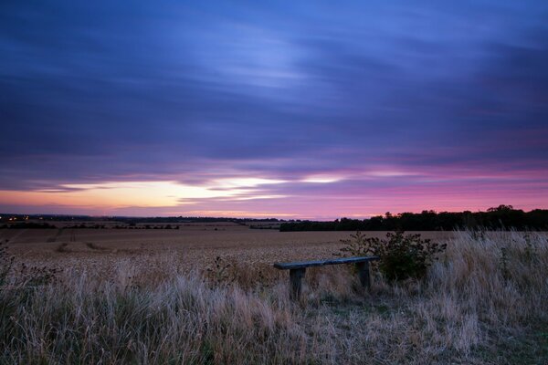 Una tienda solitaria en medio de un campo en el fondo de una densa puesta de sol malva