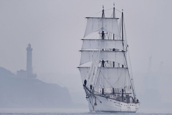 Voilier pendant le brouillard dans la mer près du phare