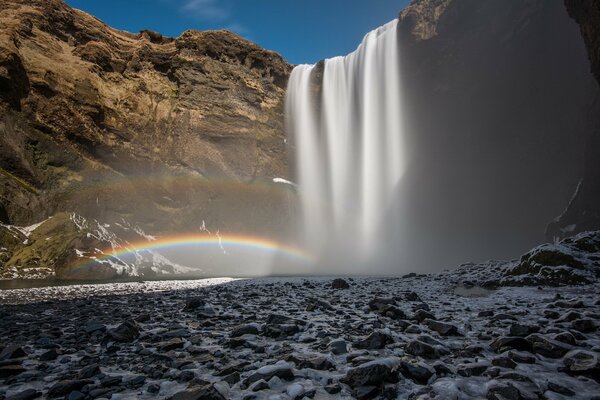 Cascada y arco iris contra el cielo azul