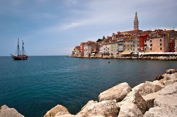 The yacht sails into the sea near the houses of Croatia