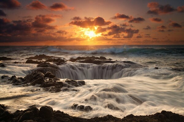 Wasserfalltrichter im Meer bei Sonnenuntergang