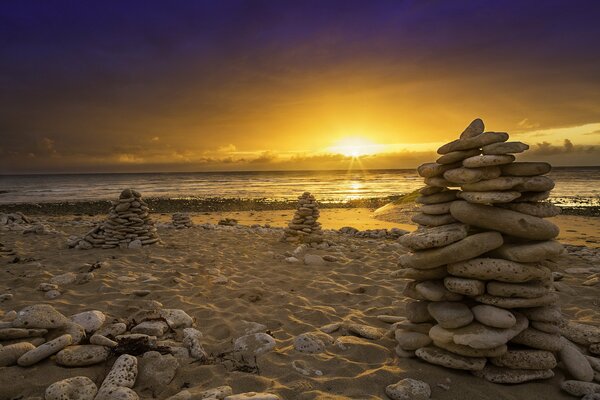 Piedras en el fondo de la puesta de sol del mar