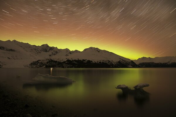 Night landscape of the lake surrounded by snowy mountains