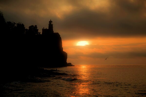 Tramonto sul mare vicino alla scogliera con faro