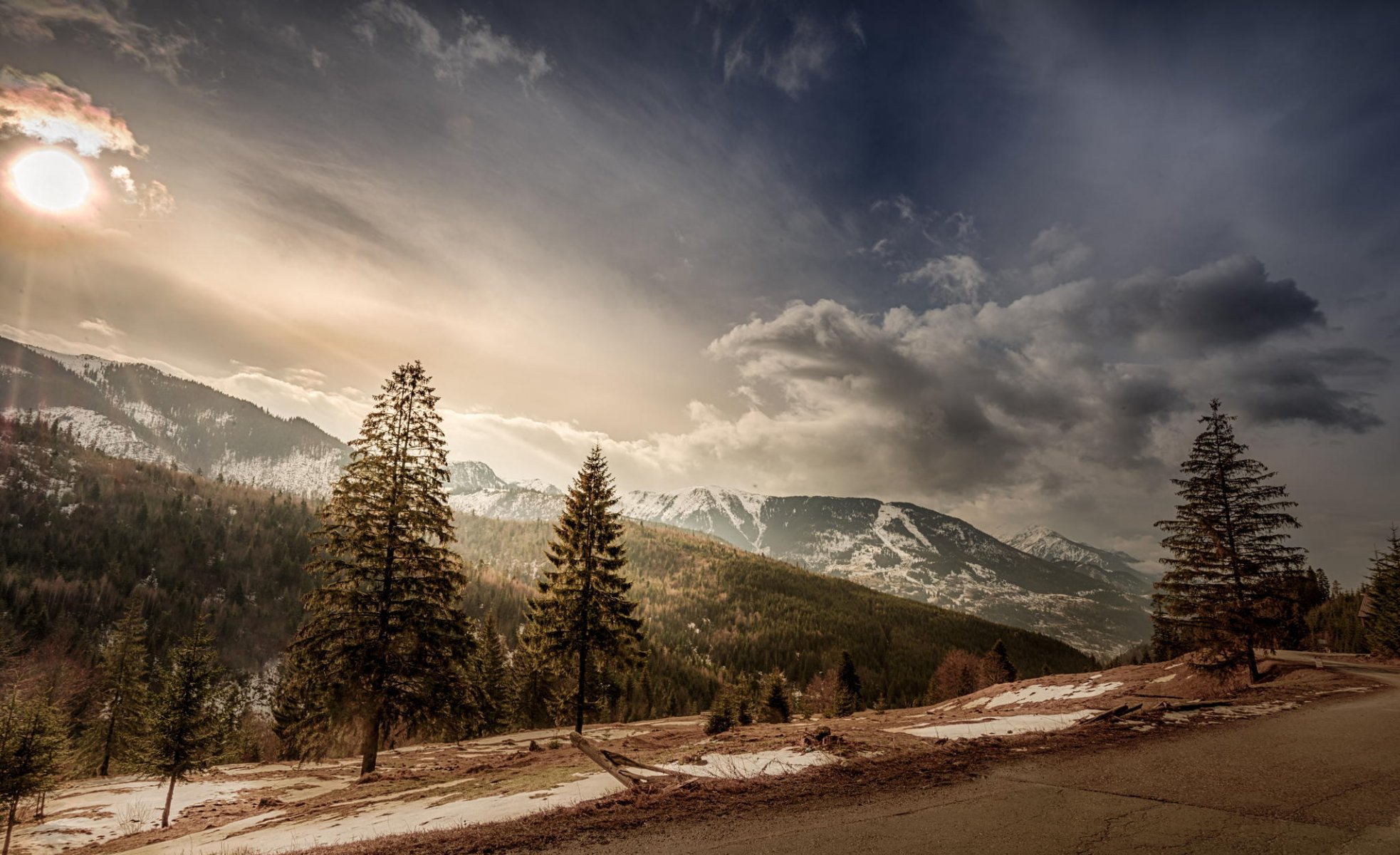 rumania árboles montañas picos nieve sol nubes cielo carretera pendiente paisaje