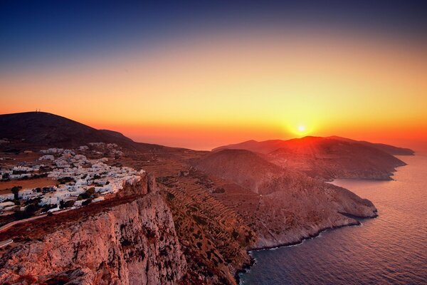 Sur la falaise se dressent les maisons avec vue sur un beau coucher de soleil