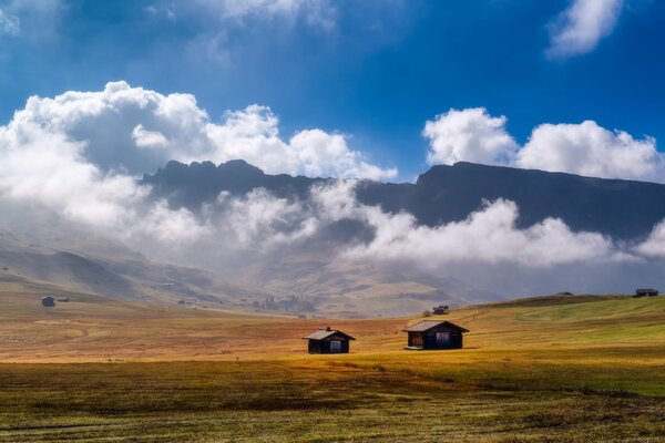 Nella valle ci sono due case sullo sfondo di enormi montagne