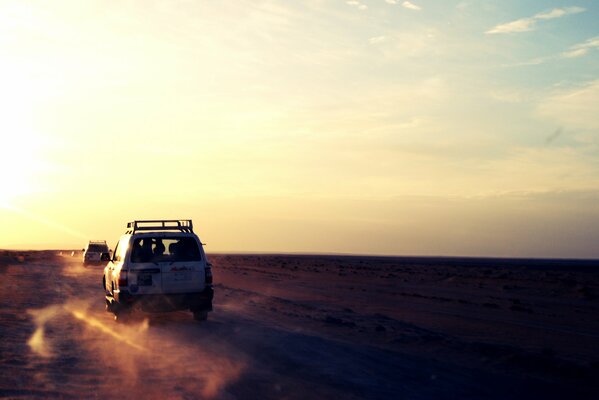 Dans le désert, deux voitures roulent sur le sable