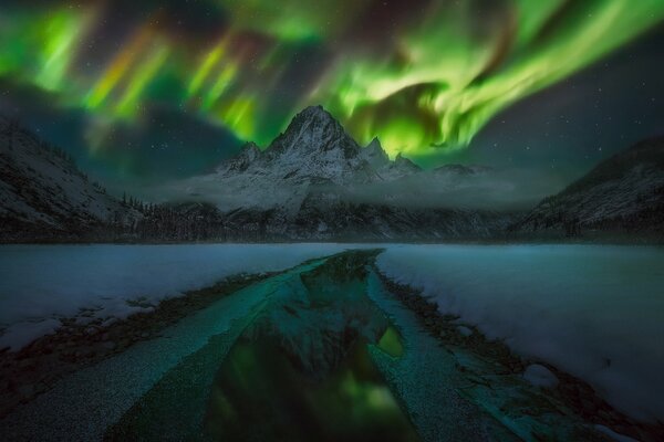 Aurora boreale sopra le montagne strada nella foresta