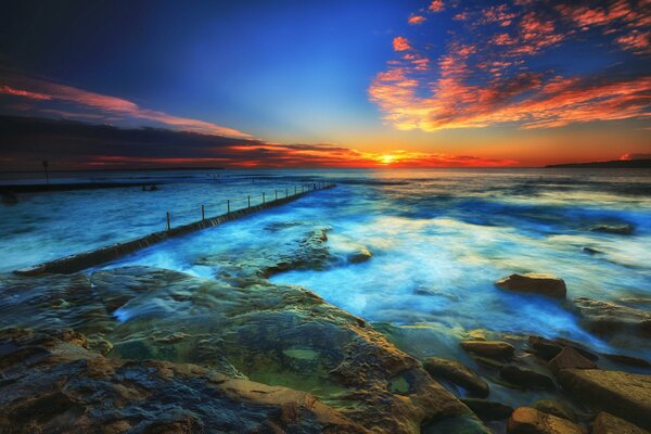 Puesta de sol en el mar. Piedras y nubes